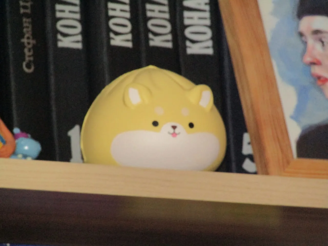 Жёлтая squishy-игрушка на полке между книгами